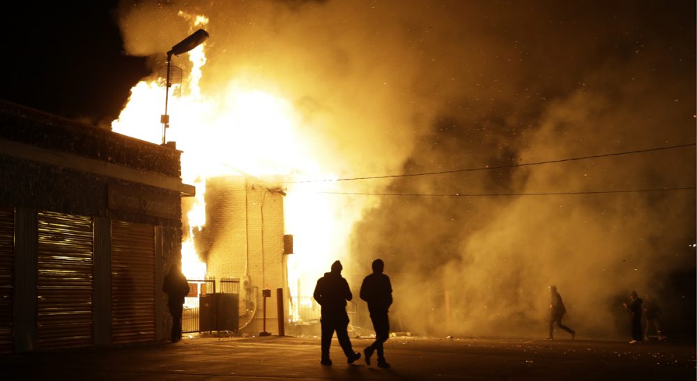 Reflecting on the heaviness of the top news stories of the year, and evaluating a common link between them. Pictured: Buildings on fire in Ferguson, Missouri after the announcement of the grand jury decision. (Jeff Roberson/AP)
