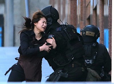 A hostage runs to armed tactical response police officers for safety after she escaped from a cafe under siege at Martin Place.  (Rob Griffith/AP)
