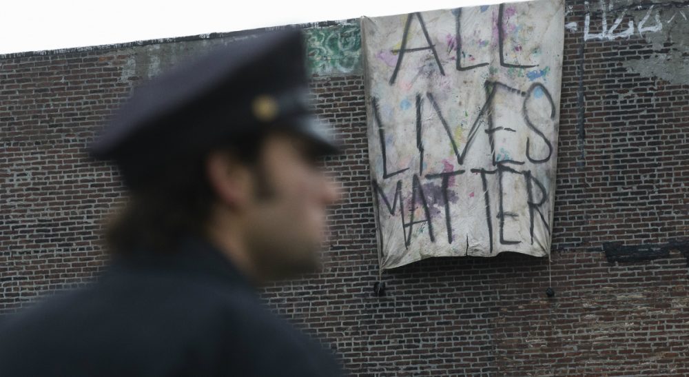 A sign that reads &quot;ALL LIVES MATTER&quot; is hung from a building near a makeshift memorial at the site where NYPD officers Rafael Ramos and Wenjian Liu were murdered in the Brooklyn borough of New York, Monday, Dec. 22, 2014. Police say Ismaaiyl Brinsley ambushed the two officers in their patrol car in broad daylight Saturday, fatally shooting them before killing himself inside a subway station. (John Minchillo/AP)