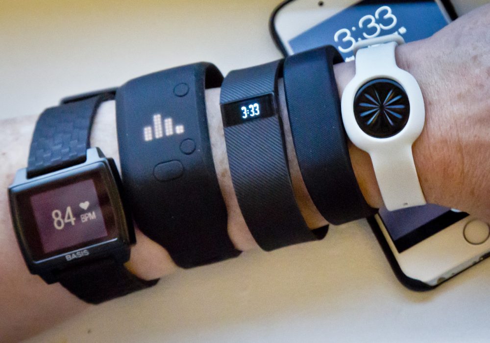 From left: Fitness trackers Basis Peak, Adidas Fit Smart, Fitbit Charge, Sony SmartBand and Jawbone Move are posed for a photo next to an iPhone in 2014. (Bebeto Matthews/AP)