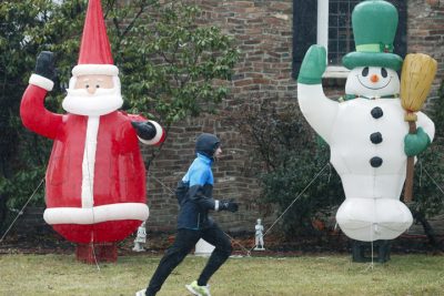A man runs in the rain past an inflatable Santa and snowman on Washington Avenue on Tuesday, Dec. 23, 2014, in Albany, N.Y.  In the busy holiday season, it can sometime be hard to remember to say thanks. (AP)
