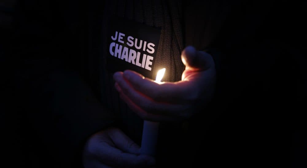 A man holds a candle and a sticker reading &quot; I am Charlie&quot;, during a demonstration in Paris, Wednesday, Jan. 7, 2015. Three masked gunmen shouting &quot;Allahu akbar!&quot; stormed the Paris offices of a satirical newspaper, Charlie Hebdo, Wednesday, killing 12 people, including its editor, before escaping in a car. It was France's deadliest postwar terrorist attack. (Christophe Ena/AP)