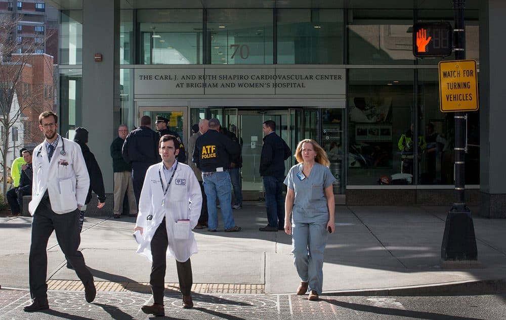 Law enforcement officials and hospital staff are outside the Shapiro building at Brigham and Women’s Hospital in Boston Tuesday, where a doctor was critically shot. (Robin Lubbock/WBUR)