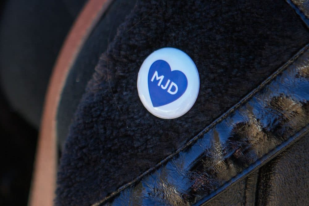 A woman wears a button honoring Michael Davidson at his funeral service Friday. (Jesse Costa/WBUR)