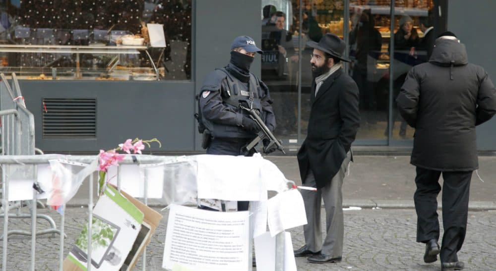 A police officer talks with a Jewish man outside the kosher grocery where Amedy Coulibaly killed four people in a terror attack, in Paris, Tuesday, Jan.20, 2015. Brothers Said and Cherif Kouachi and their friend, Amedy Coulibaly, killed 17 people at the satirical newspaper Charlie Hebdo, a kosher grocery and elsewhere. (Francois Mori/AP)