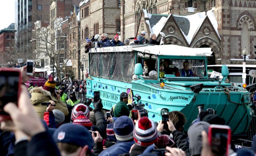 Patriots owner Robert Kraft holds up the Lombardi Trophy his team won in Sunday's Super Bowl while riding in Boston's duck boat rolling rally Wednesday. (Robin Lubbock/WBUR)