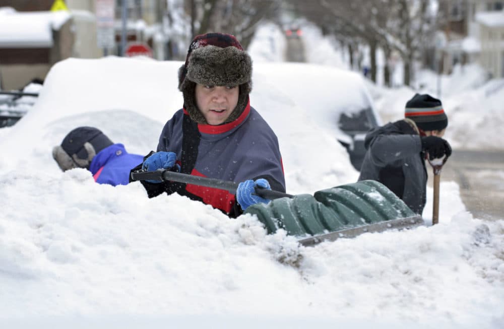 Will Chapman, of Oakland, Calif., digs out his car from between snow piles near the house he was visiting in Somerville, Mass., Tuesday. The latest snowstorm left the Boston area with another two feet of snow, and while many businesses closed for the weather, stores selling winter equipment are staying open for a steady influx of customers. (Josh Reynolds/AP)
