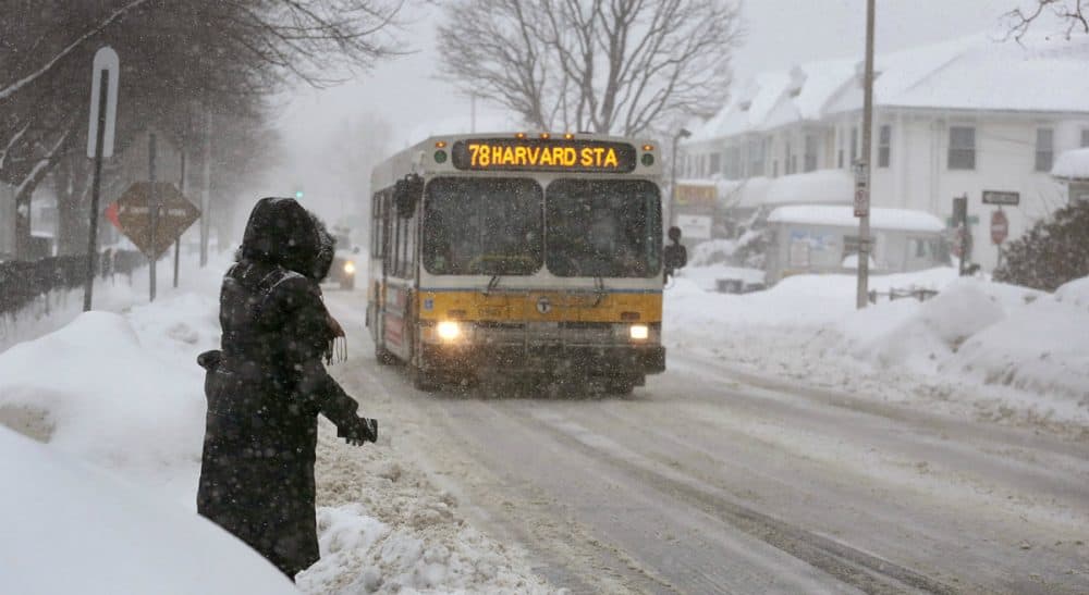 J. Kates: When public transportation grinds to a halt, we throw our iciest snowballs at the people working to get and keep the trains and buses moving. In this photo, Alma Az, 43, waits for a bus on Concord Ave. Cambridge, as she makes her way to work in Copley Square, Mon., Feb. 9, 2015. (Robin Lubbock/WBUR)