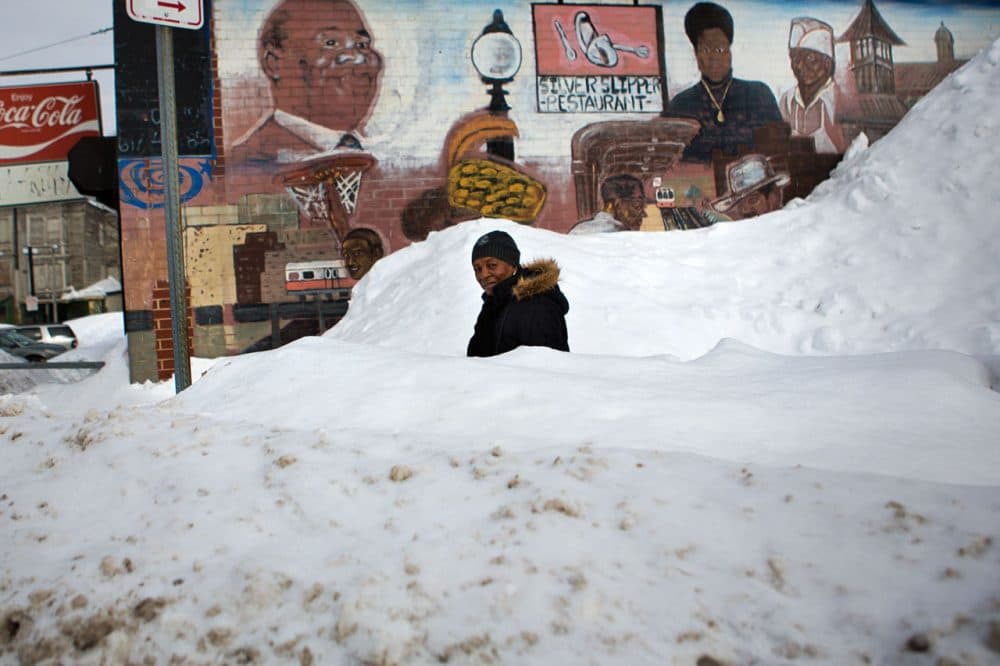 Pauline Sheridan, 82, navigates a small winding path through a large snow bank in front of the Silver Slipper Restaurant at the intersection of Washington St and Malcolm X Blvd. Many people in Dudley Sq. complain the roads and sidewalks around Roxbury have not been cleared properly. (Jesse Costa/WBUR)