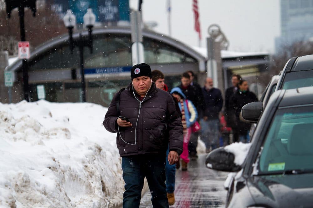 Blocked by snow, commuters walk in the street after leaving Maverick station Thursday. (Jesse Costa/WBUR)