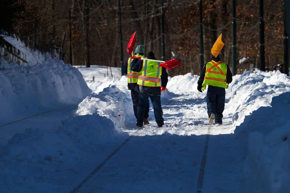 Workers clear snow from the MBTA's Mattapan trolley line on Friday. The line reopened on Monday. (Jesse Costa/WBUR)