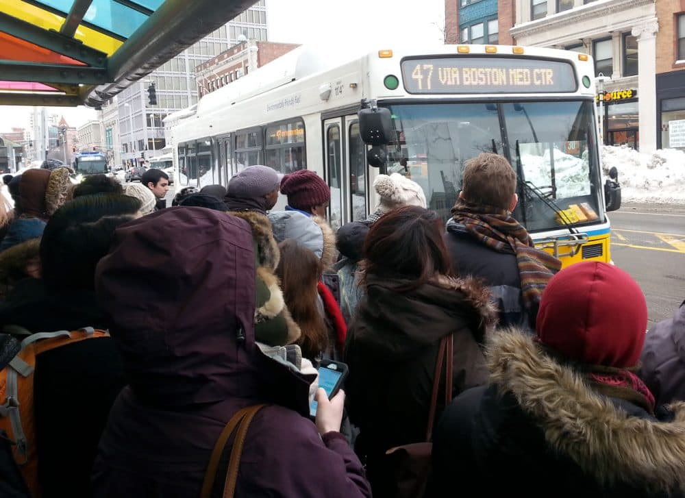 Commuters wait for a MBTA bus in Central Square in Cambridge Thursday. (Zeninjor Enwemeka/WBUR)