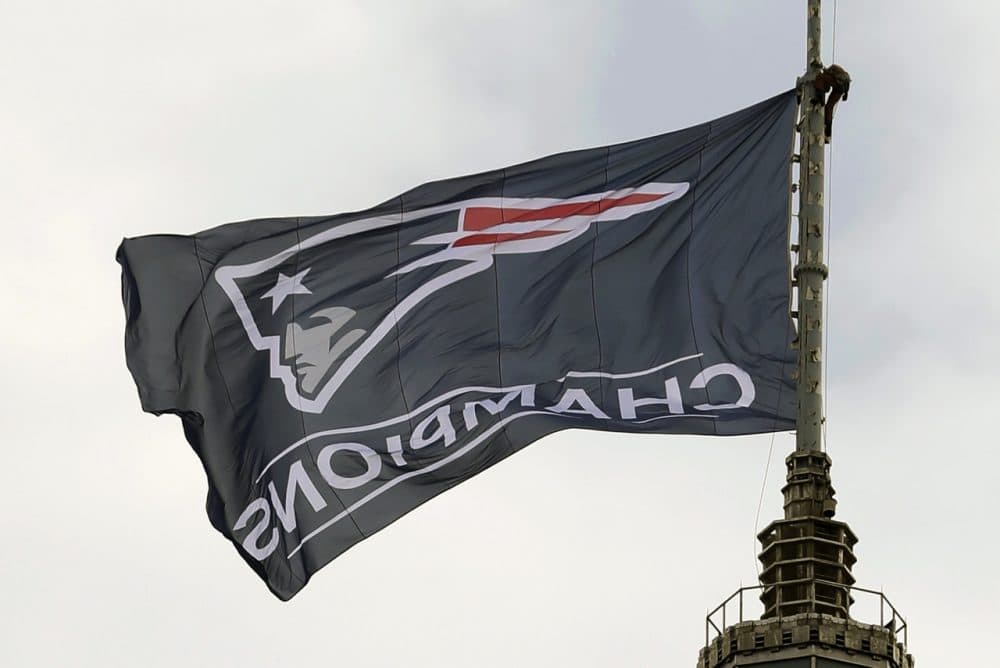 A worker secures a New England Patriots flag atop a building prior to a victory parade in Boston Wednesday to honor the Patriots win over the Seattle Seahawks 28-24 in Super Bowl XLIX Sunday. (Steven Senne/AP)