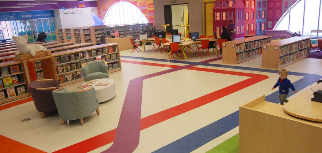 “We want people to know they’re in the library, of course, but also to know they’re in Boston,” Colford says. Part of the way this makes its way into the Children’s Library is colored stripes running along the floor that echo MBTA train maps. (Greg Cook)