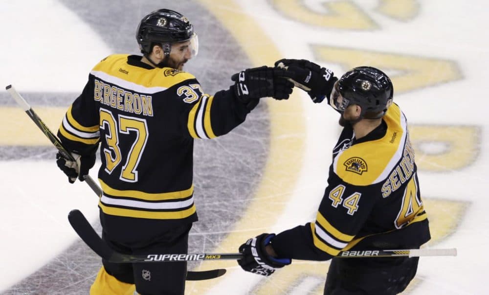 Boston Bruins center Patrice Bergeron (37) is congratulated by teammate Dennis Seidenberg after his goal against the Tampa Bay Lightning during the third period of an NHL hockey game in Boston, Thursday, March 12, 2015. (Charles Krupa/AP)