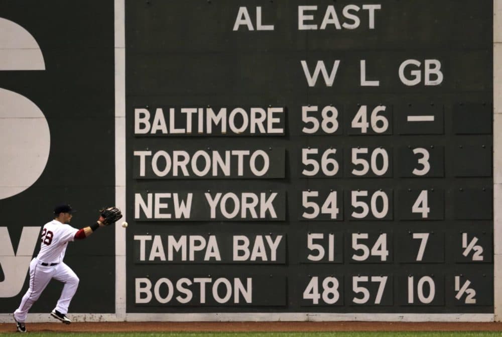Boston Red Sox left fielder Daniel Nava plays a single off the AL East standings scoreboard, with the Red Sox posted in last place in the division during a game at Fenway Park in Boston on July 28, 2014. (Charles Krupa/AP)