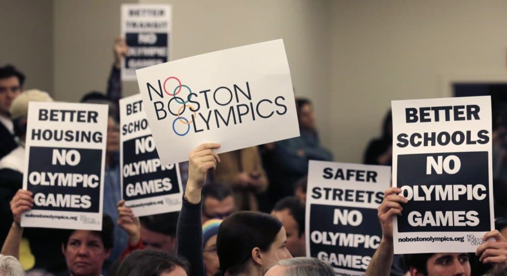 People hold up placards against bringing the Olympic Games to Boston during the first public forum regarding the city's 2024 Olympic bid in February, 2015. (Charles Krupa/AP)