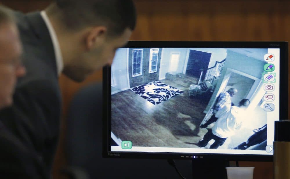 Former New England Patriots football player Aaron Hernandez, center, looks on as a still frame from surveillance video is displayed on a monitor during his murder trial Thursday. (Steven Senne/AP/Pool)