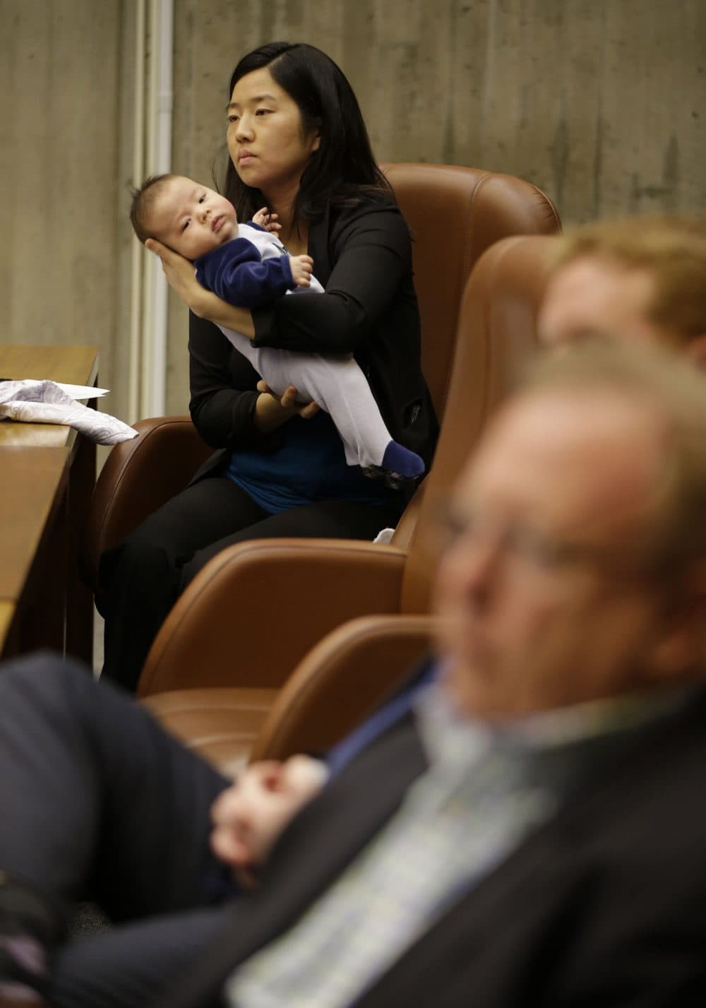 Boston City Councilwoman Michelle Wu holds her eleven week-old son Blaise Pawarski as members of Boston 2024 answer questions during the first meeting of the Boston City Council on the city's bid to be awarded the 2024 Summer Olympics, Friday March 6, 2015, at City Hall in Boston.  (AP)