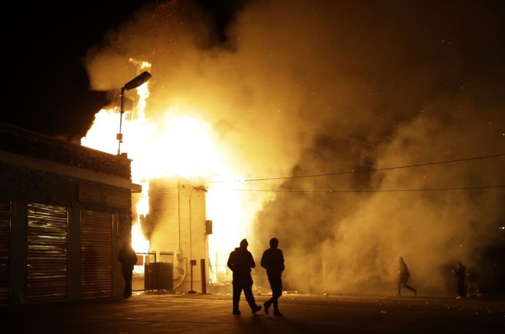 In this Monday Nov. 24, 2014 file photo, people walk away from a storage facility on fire after the grand jury decision was announced in Ferguson. (Jeff Roberson/AP)