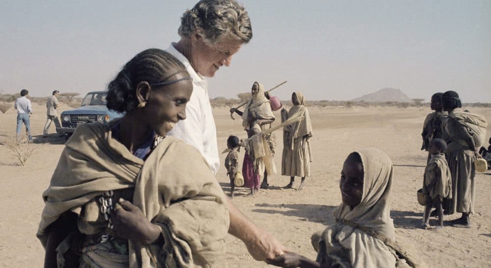 Sen. Edward Kennedy, center left, has a smile and a handshake for an unidentified young refugee in the Tuki-Baab famine refugee camp during a visit, Tuesday, Dec. 27, 1984, Tuki-Baab, Eastern Sudan. (Robert Dear/AP)