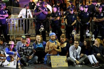 In this file photo, protesters sit at the intersection of Wall St. and Broad St. in New York, Monday, Sept. 22, 2014. The protesters, many who were affiliated with Occupy Wall Street, were trying to draw attention to the connection between capitalism and environmental destruction. (AP)