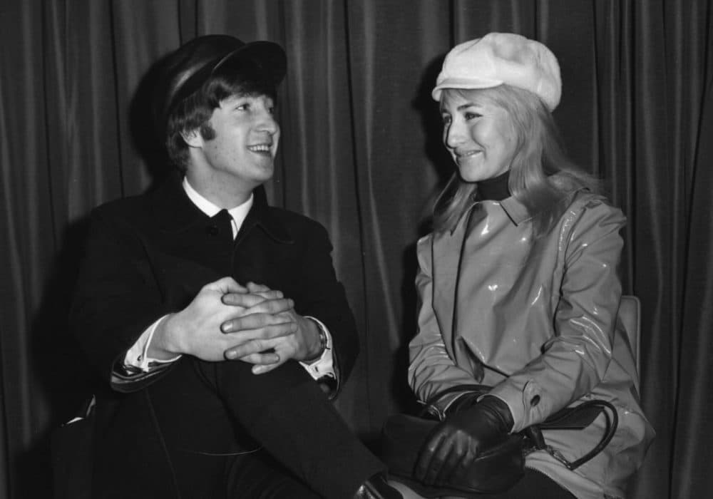 Singer and songwriter John Lennon (1940 - 1980), of The Beatles, with his wife Cynthia, wait for a flight to New York from London Airport, Feb. 7, 1964. (Keystone/Getty Images)