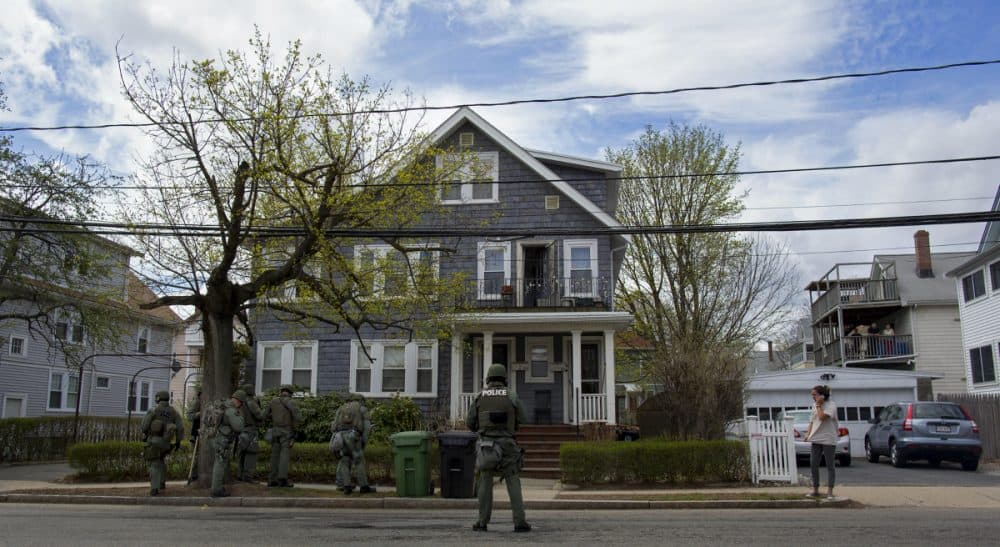 Heavily armed police officers do house to house searches in the neighborhoods of Watertown, Mass. Friday, April 19, 2013, as a massive search continued for one of two suspects in the Boston Marathon bombing. (Craig Ruttle/AP)