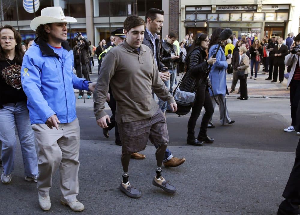 Boston Marathon survivor Jeff Bauman, right, walks past one of two blast sites with Carlos Arredondo, who helped save his life, near the finish line of the Boston Mararthon in Boston, Wednesday, April 15, 2015. Boston marked the second anniversary of the 2013 marathon bombings with a subdued remembrance that includes a moment of silence, the pealing of church bells and a call for kindness. (Charles Krupa/AP)