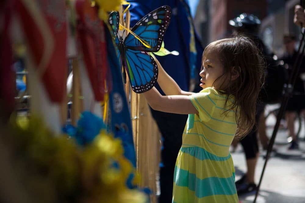 Six-year-old Jaslene Oyola, of Roxbury, hangs a butterfly on a memorial on Boylston Street Wednesday in honor of the Boston Marathon victims. (Jesse Costa/WBUR)