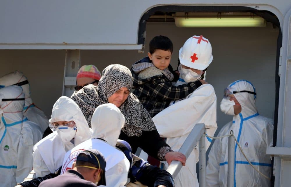 Rescued migrants are assisted down the gangplank by Italian Red Cross workers as they disembark from the Italian Navy vessel Bettica after arriving in the Sicilian harbor of Augusta on April 22, 2015. European governments came under increasing pressure to tackle the Mediterranean's migrant crisis ahead of an emergency summit, as harrowing details emerged of the fate of hundreds who died in the latest tragedy. (Alberto Pizzoli/AFP/Getty Images)