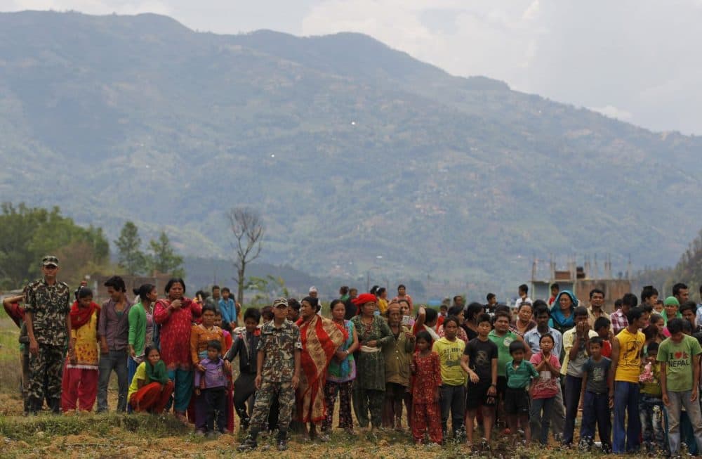 Nepalese villagers watch as relief material is brought in an Indian air force helicopter for victims of Saturday's earthquake at Trishuli Bazar in Nepal, Monday. (Altaf Qadri/AP)