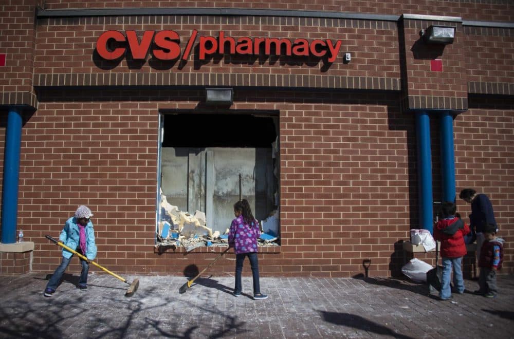 Young children sweep up the area outside the CVS Pharmacy in Baltimore, Maryland, April 28, 2015, that was set on fire during rioting last night. Riot police and National Guard troops stood guard on the smoldering streets of Baltimore Tuesday after protesters incensed by the death of a young black man in police custody went on the rampage, torching cars and buildings and looting stores. Fires continued to burn in the mainly black northeastern city, where a curfew was set to take effect Tuesday evening after a day of riots that dragged on into Monday night. The state of Maryland declared a state of emergency after rioters ransacked shops, making off with armloads of merchandise. Schools were closed Tuesday a safety measure. (Jim Watson/AFP/Getty Images)