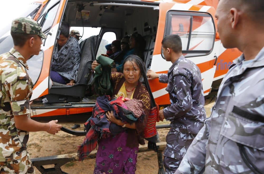 A mother injured in Saturday's massive earthquake carries her newborn child as she arrives by helicopter from the heavily-damaged Ranachour village at a landing zone in the town of Gorkha, Nepal, Tuesday, April 28, 2015. Helicopters crisscrossed the skies above the high mountains of Gorkha district on Tuesday near the epicenter of the weekend earthquake, ferrying the injured to clinics, and taking emergency supplies back to remote villages devastated by the disaster. (Wally Santana/AP)