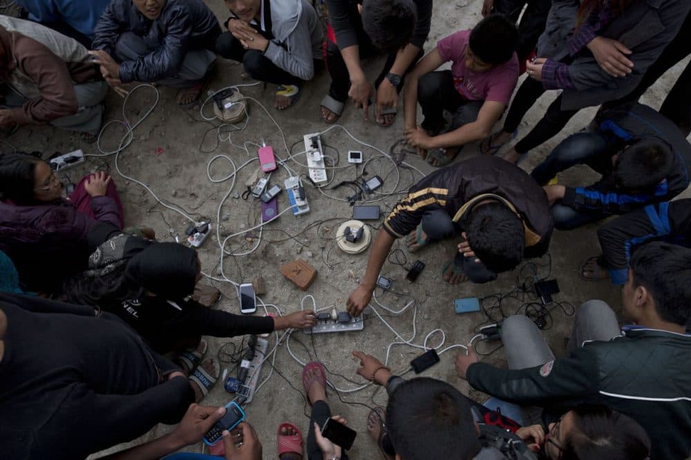 Nepalese villagers charge their cell phones in an open area in Kathmandu, Nepal, Monday, April 27, 2015. (Bernat Armangue/AP)