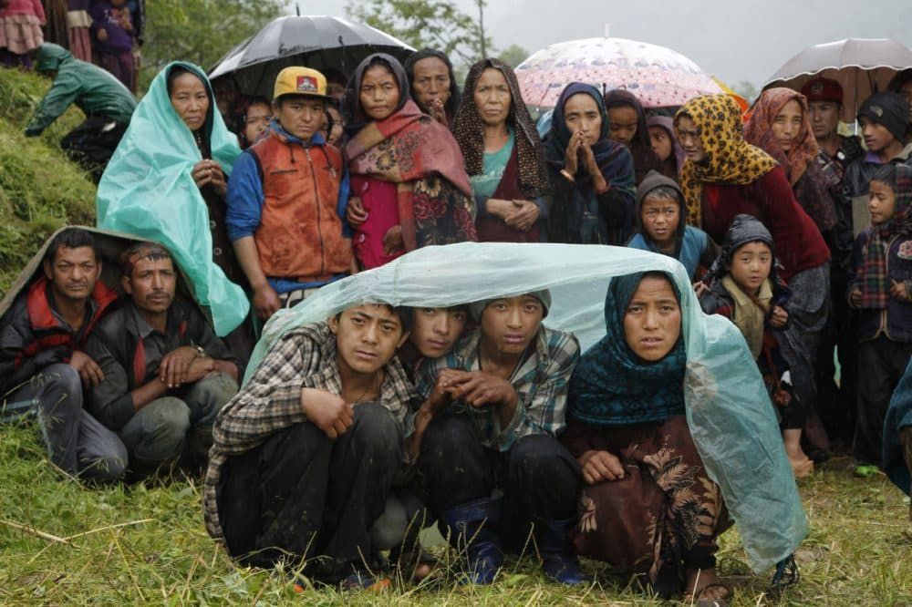 Villagers wait in the rain as an aid relief helicopter lands at their remote mountain village of Gumda, near the epicenter of Saturday's massive earthquake in the Gorkha District of Nepal on Wednesday. (Wally Santana/AP)