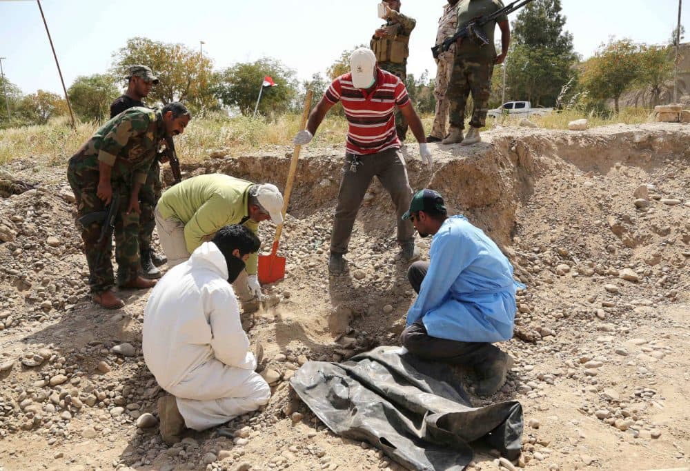 An Iraqi forensic team works at the site of a mass grave, believed to contain the bodies of Iraqi soldiers killed by Islamic State group militants when they overran Camp Speicher military base last June, in Tikrit, Iraq, 80 miles north of Baghdad, Thursday, April 9, 2015. (Karim Kadim/AP)