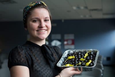 On Point producer Abigail Collins shows off her freshly prepared cut black olives. (Robin Lubbock / WBUR)