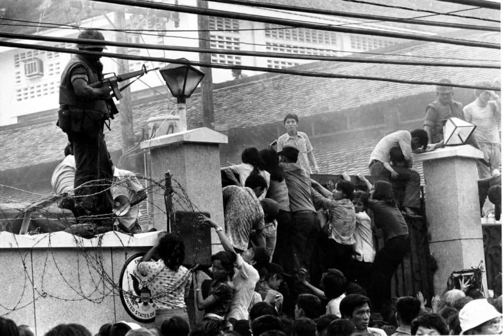 In this April 29, 1975, file photo, mobs of Vietnamese people scale the wall of the U.S. Embassy in Saigon, trying to get to a helicopter pickup zone. (Neal Ulevich/AP)