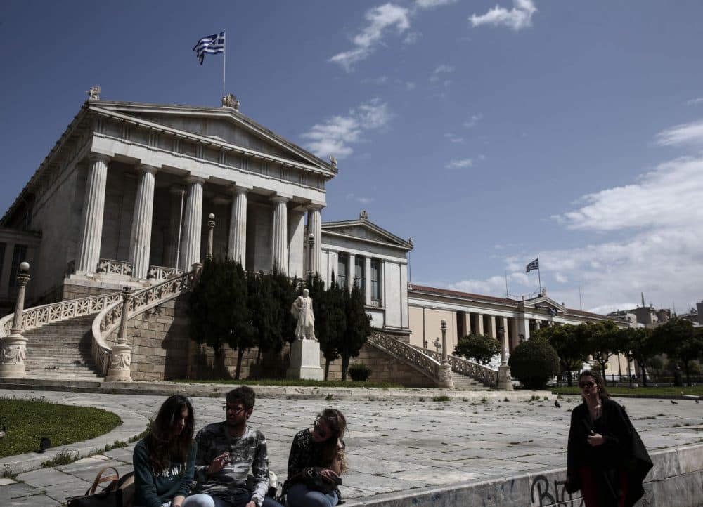 Young people sit in front of the National Library of Athens on Monday, April 6. Greece and its international creditors are still struggling to agree on a list of economic reforms that are deemed necessary for the country to unlock emergency funds. (Yorgos Karahalis/AP)