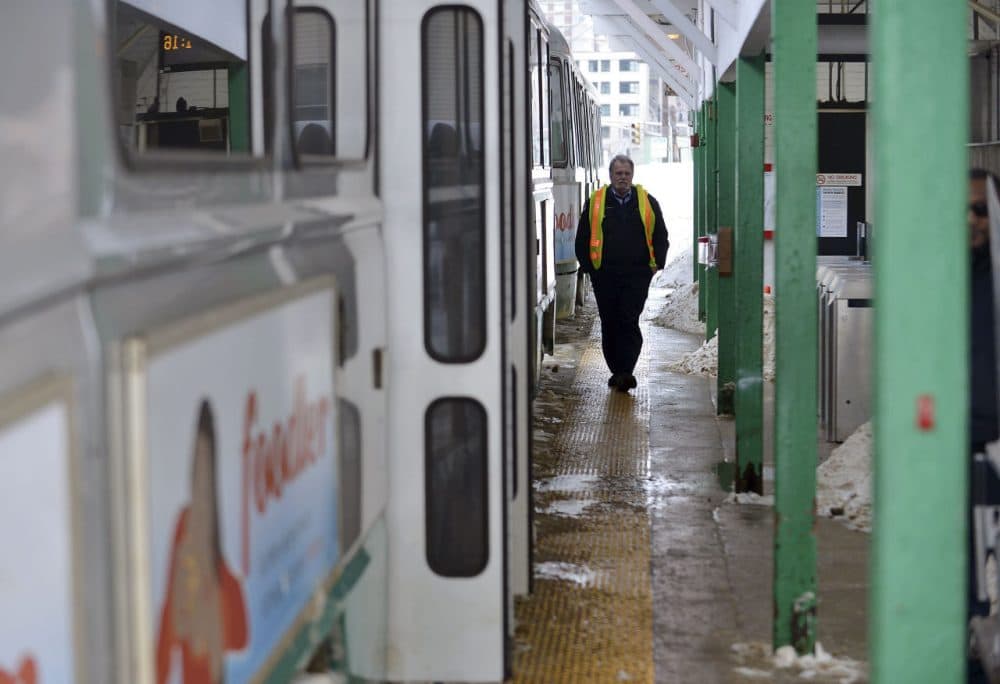 An MBTA Employee walks along the platform next to an idle transit train at the Leachmere T station in Cambridge on Feb. 10, 2015. (Josh Reynolds/AP)