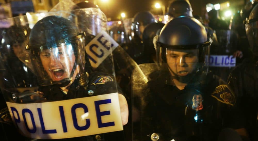 Police in riot gear push back on media and a crowd gathering in the street after a 10 p.m. curfew went into effect Thursday, April 30, 2015, in Baltimore. The curfew was imposed after unrest in the city over the death of Freddie Gray while in police custody. (David Goldman/AP)