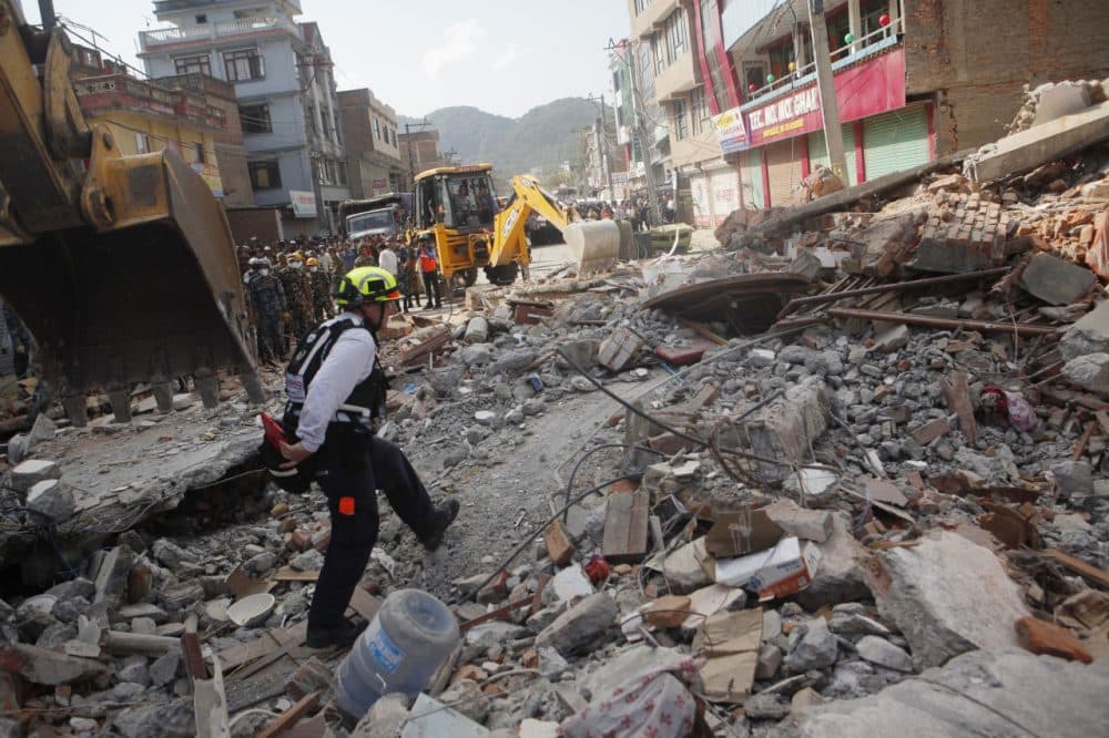 A rescue worker from USAID inspects the site of a building that collapsed in an earthquake in Kathmandu, Nepal, Tuesday, May 12, 2015. A major earthquake has hit Nepal near the Chinese border between the capital of Kathmandu and Mount Everest less than three weeks after the country was devastated by a quake. (Niranjan Shrestha/AP)
