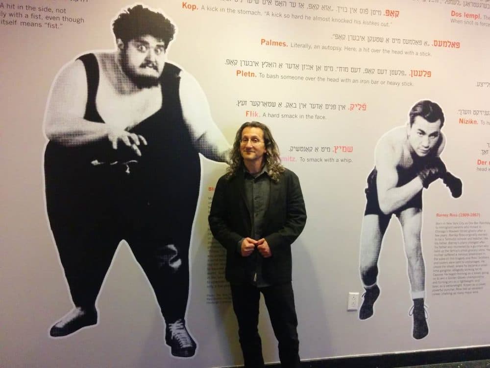 Eddy Portnoy poses with the exhibit he curated on Yiddish street fighting as well as Jewish wrestlers in Europe and the U.S. including Martin Levy (left), who weighed in at over 600 pounds and was aptly nicknamed, &quot;The Blimp.&quot;