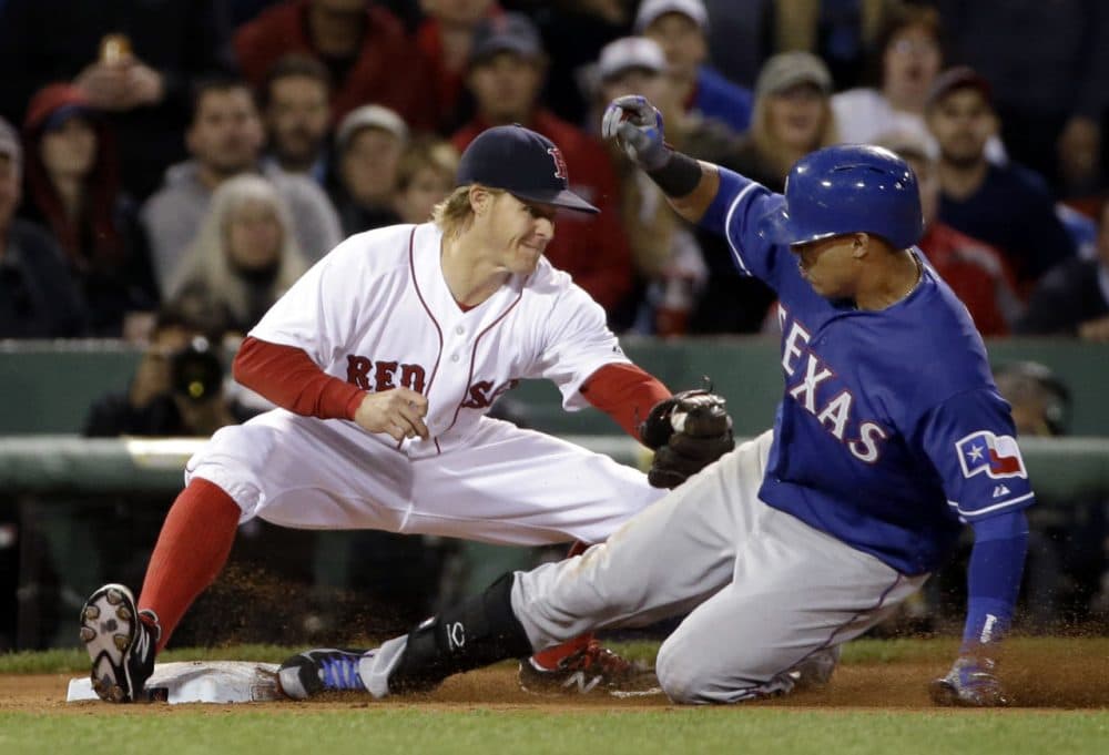 Texas Rangers' Leonys Martin slides into third base as Boston Red Sox third baseman Brock Holt attempts a tag during the seventh inning at Fenway Park on Wednesday, May 20, 2015.  (Elise Amendola/Associated Press)