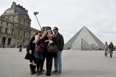 Tourists use a selfie-stick to take a picture of themselves in front of the Pyramid of the Louvre in Paris on March 7, 2015. (Dominique Faget/AFP/Getty Images)