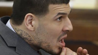 Sporting a new neck tattoo, Aaron Hernandez sits at the defense table during his arraignment in Suffolk Superior Court Thursday (Stephan Savoia/AP/Pool)