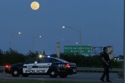 An armed police officer stands guard on a road near the Curtis Culwell Center where a provocative contest for cartoon depictions of the Prophet Muhammad was held Sunday, May 3, 2015, in Garland, Texas. The contest was put on lockdown Sunday night and attendees were being evacuated after authorities reported a shooting outside the building. (AP)