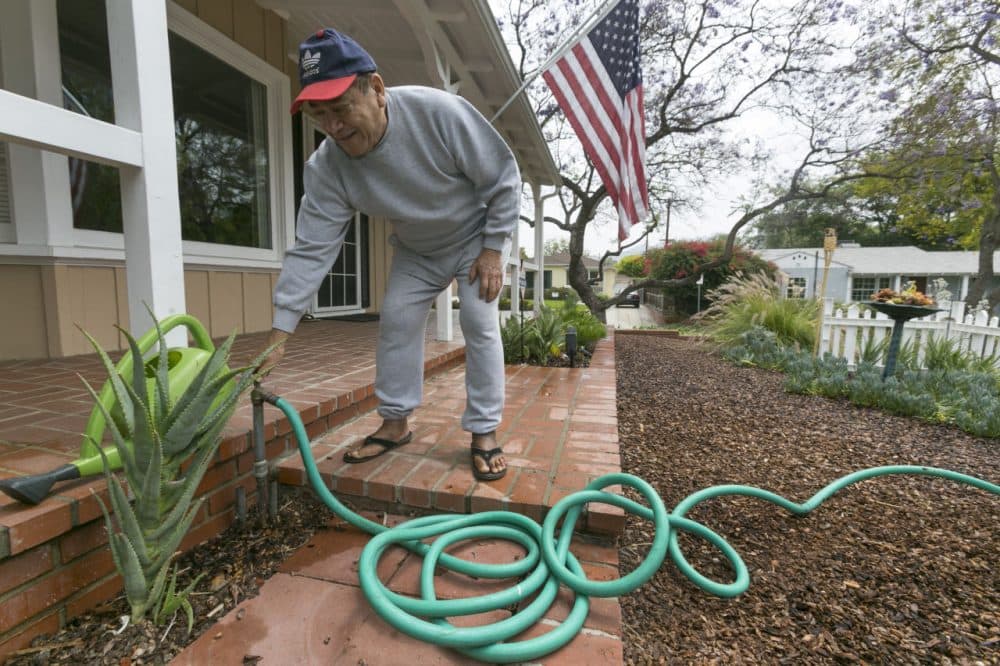 Raymond Aleman closes his water hose after watering his new drought-resistant garden at his home in the Studio City neighborhood in Los Angeles, Wednesday, May 27, 2015. (Damian Dovarganes/AP)