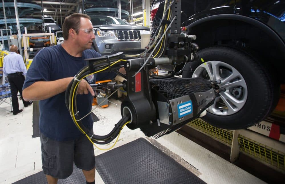 A worker mounts tires on a Chrysler SUV as it moves along the assembly line at the Jefferson North Assembly Plant in Detroit Michigan, August 7, 2012. (Geoff Robins/AFP/Getty Images)